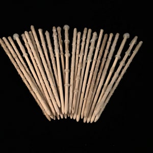 May include: A collection of wooden wands with white tips, arranged in a fan shape. The wands are approximately 12 inches long and have a natural wood finish.