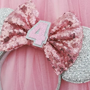Pu&ograve; includere: Fascia per capelli con glitter rosa e argento con un fiocco rosa e il numero "4" su di essa. La fascia &egrave; progettata per assomigliare alle orecchie di Topolino.