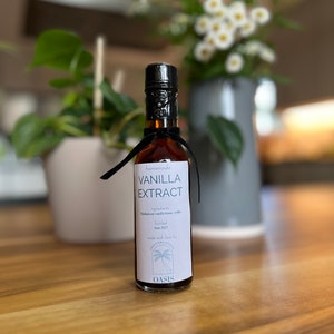 May include: A small glass bottle of homemade vanilla extract with a black label that reads "Homemade Vanilla Extract" and lists the ingredients as "Madagascar vanilla beans, vodka". The label also states that the extract was bottled in June 2023 and made with love by "Creation with Love by Oasis".
