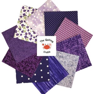 May include: A collection of fabric squares in various shades of purple, arranged in a circular pattern. The fabrics feature floral, polka dot, and textured designs. A square in the center displays the text "The Quilting Crabb" with a crab logo.