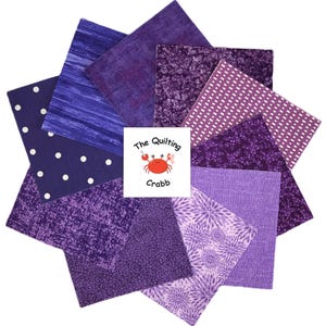 May include: A collection of purple fabric squares arranged in a circular pattern. The fabrics feature various textures and patterns, including polka dots, floral designs, and marbled effects. The center displays a logo with a crab.