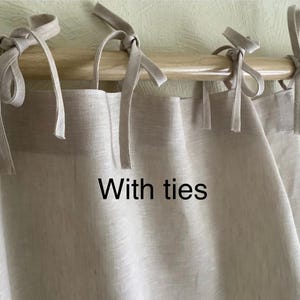 May include: A pair of beige linen curtains with ties. The curtains are hanging on a wooden rod.