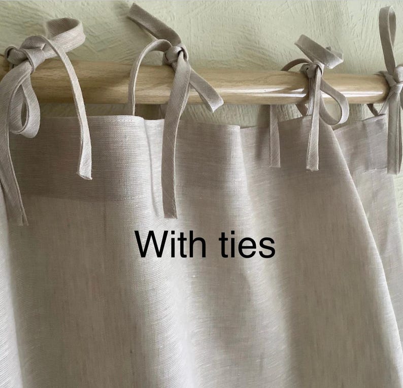 May include: A pair of beige linen curtains with ties. The curtains are hanging on a wooden rod.