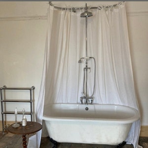 May include: A white clawfoot bathtub with a chrome shower head and shower curtain in a bathroom.