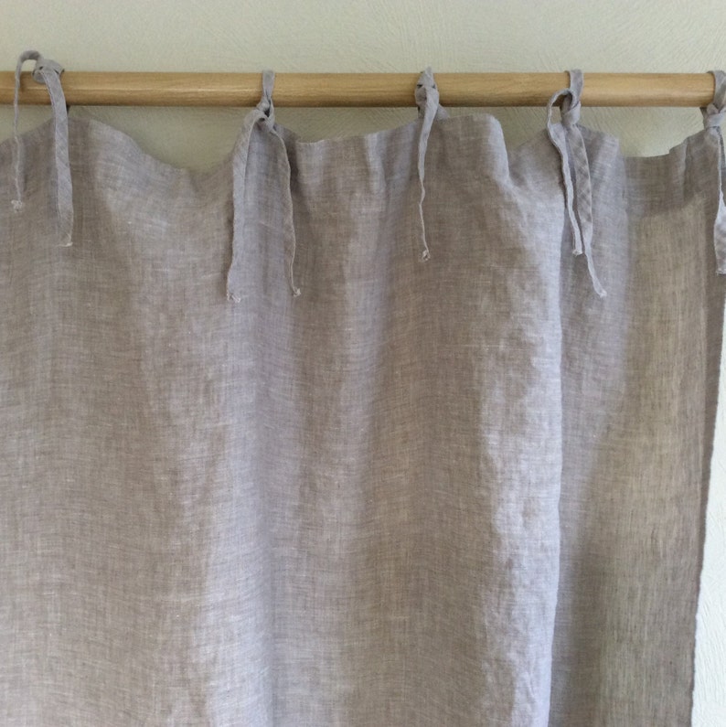 May include: A pair of light gray linen curtains with a wooden rod and simple tie-backs.
