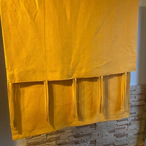 May include: A pair of yellow linen curtains with a gathered top and a bottom row of tassels.