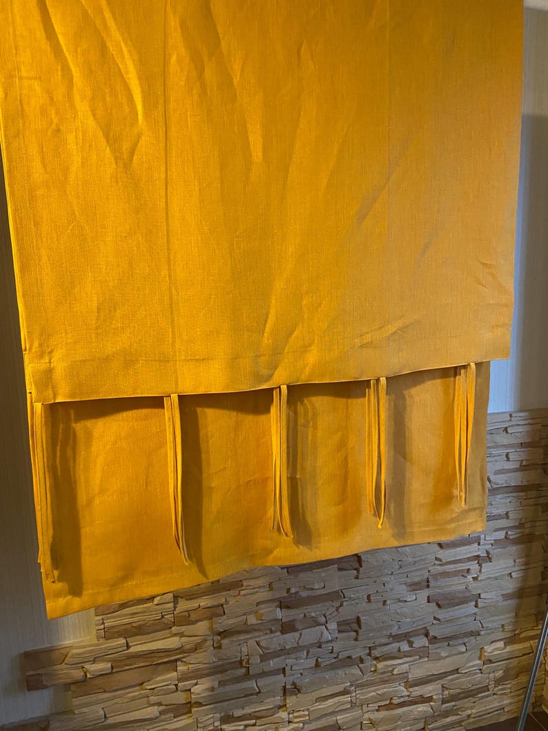 May include: A pair of yellow linen curtains with a gathered top and a bottom row of tassels.