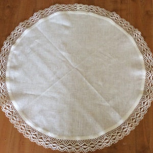 Puede incluir: Mantel redondo blanco con un delicado borde de encaje. El mantel est&aacute; hecho de una tela suave, similar al lino.