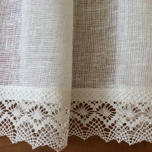 May include: White sheer curtains with a delicate lace trim. The curtains are made of a lightweight fabric and have a subtle texture.