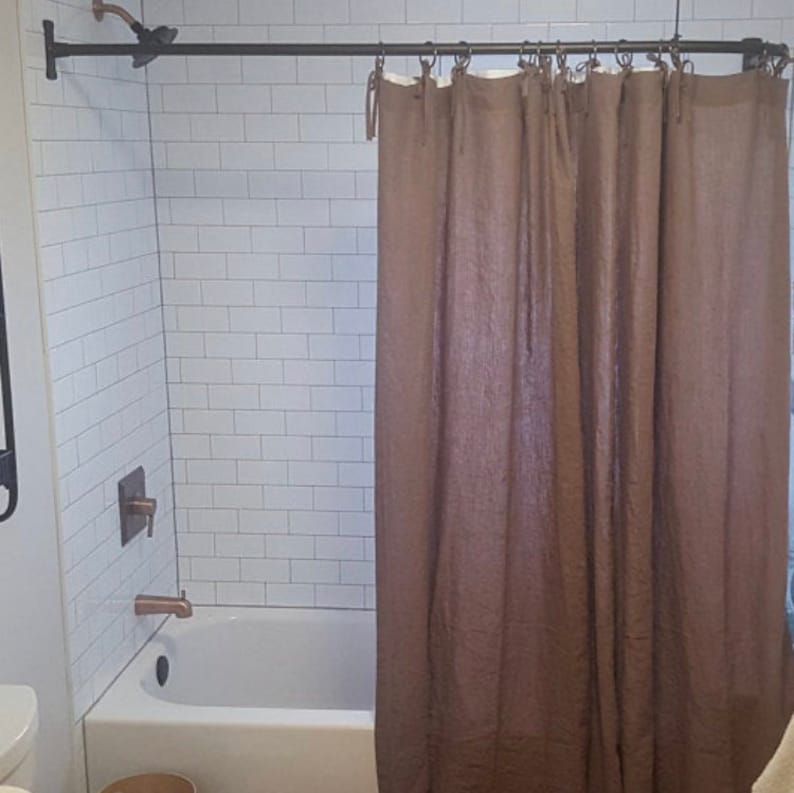 May include: A white tiled shower with a brown linen shower curtain. The shower has a brushed nickel shower head and a single handle brushed nickel shower faucet.