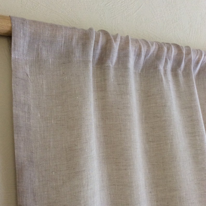 May include: A pair of light brown linen curtains hanging from a wooden rod. The curtains are made of a natural fabric with a subtle texture.