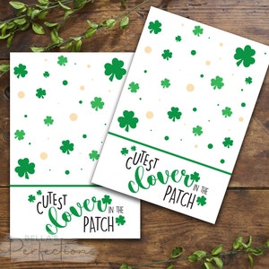 Può includere: Due carte stampabili con sfondo bianco e disegni di trifoglio verde. Il testo sulle carte recita "Cutest Clover in the Patch".
