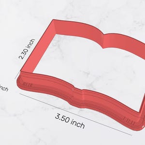 May include: Red plastic cookie cutter shaped like an open book. The cutter is 3.50 inches wide and 2.30 inches tall. The area of the cutter is 7.4 inches.