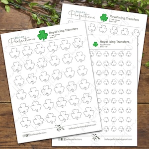 Könnte beinhalten: Drei Blätter mit bedruckbaren Übertragungen für königlichen Zuckerguss mit dreiblättrigen Kleeblatt-Designs in verschiedenen Größen. Die Blätter sind mit "Royal Icing Transfers" beschriftet, wobei die Größe jedes Kleeblatt-Designs angegeben ist. Die Designs sind schwarz umrandet und bereit zum Ausschneiden und Dekorieren von Kuchen, Keksen und anderen Backwaren.