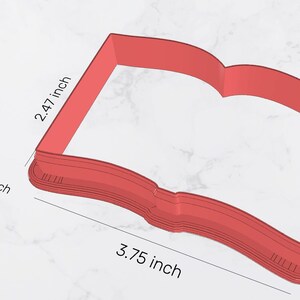 May include: Red plastic cookie cutter shaped like an open book. The cutter is 3.75 inches wide and 2.47 inches tall. The area of the cutter is 8.5 square inches.