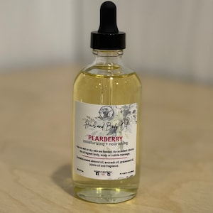 May include: A clear glass bottle with a dropper top filled with a light yellow liquid. The bottle has a white label with the text "Hair and Body Oil Pearberry moisturizing + nourishing Use on wet or dry skin as needed. An excellent choice for a fragrant body, scalp or cuticle massage. Contains sweet almond oil, avocado oil, grapeseed oil, jojoba oil and fragrance. All organic ingredients."