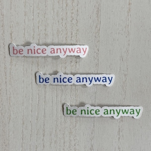 May include: Three white stickers with the text "be nice anyway" in pink, blue, and green lettering.