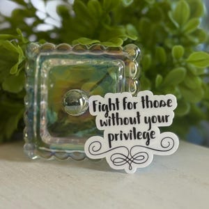 May include: White sticker with black text that reads "Fight for those without your privilege" with a decorative swirl design.