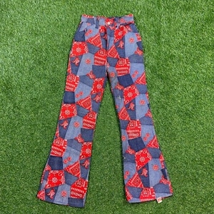 Puede incluir: Un pantalón de campana de mezclilla azul y rojo con estampado de bandana.