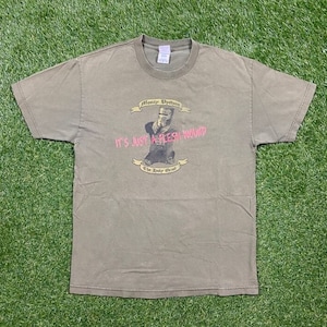 Könnte beinhalten: Ein grünes T-Shirt mit einem Aufdruck eines Ritters in Rüstung mit dem Text "Monty Python's It's Just a Flesh Wound The Holy Grail" auf der Vorderseite.