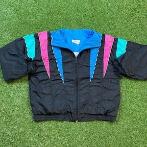 May include: A black windbreaker jacket with a blue, pink, and turquoise color block design. The jacket has a zipper closure and a stand-up collar.