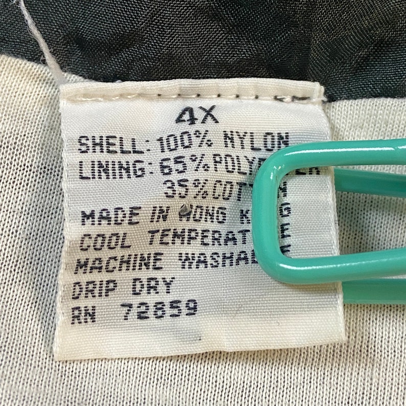 Może przedstawiać: Biała metka z czarnym tekstem, kt&oacute;ry brzmi: "4X", "SHELL: 100% NYLON", "LINING: 65% POLY", "35%COT", "MADE IN HONG K", "COOL TEMPERAT", "MACHINE WASHAL", "DRIP DRY", "RN 72859".