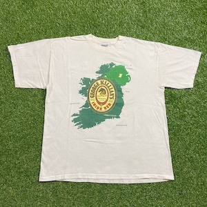 May include: White t-shirt with a graphic of a map of Ireland and a George Killian's Irish Red beer label.