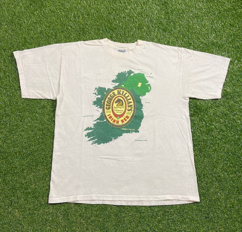May include: White t-shirt with a graphic of a map of Ireland and a George Killian's Irish Red beer label.