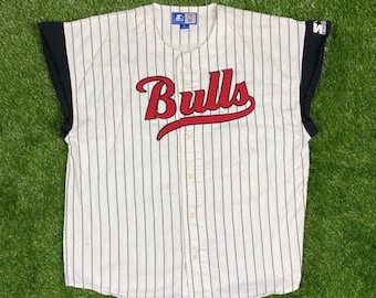 May include: White and black striped baseball jersey with a red "Bulls" logo on the front. The jersey has a button-up front and short sleeves.