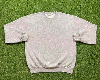 May include: A gray sweatshirt with a crew neck and long sleeves. The sweatshirt has a small tag on the bottom right side.