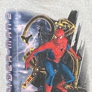 May include: Grey t-shirt featuring a graphic print of Spider-Man and Doc Ock from the film Spider-Man 2. The text "Spider-Man 2" is printed on the left side of the shirt.