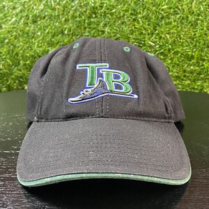 May include: Black baseball cap with a curved brim and green trim. The cap features the letters "TB" in green and blue, with a stylized design underneath. The cap is made of a durable fabric.