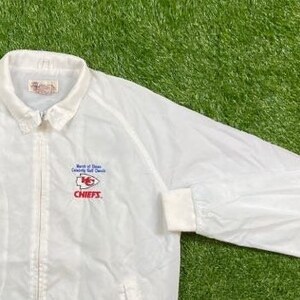 May include: White windbreaker jacket with a red, white, and blue Kansas City Chiefs logo and the text "North of Dixie County Golf Classic" and "CHIEFS".