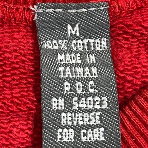 Pu&ograve; includere: Un'etichetta in bianco e nero con il testo "M", "100% Cotone", "Made in Taiwan", "P.O.C", "RN # 54023", "Rovesciare per la cura".