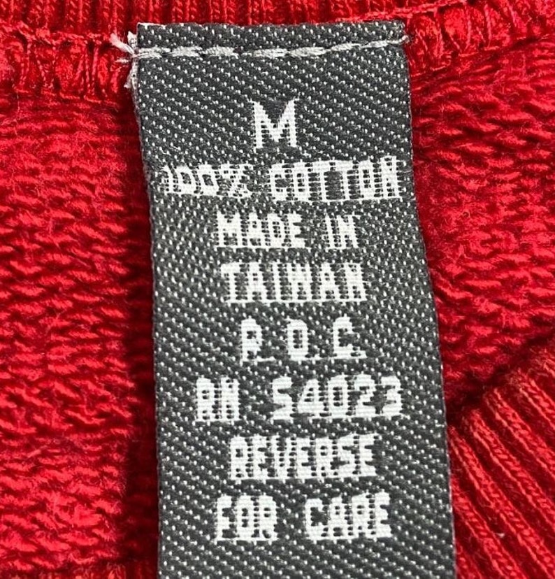 Pu&ograve; includere: Un'etichetta in bianco e nero con il testo "M", "100% Cotone", "Made in Taiwan", "P.O.C", "RN # 54023", "Rovesciare per la cura".