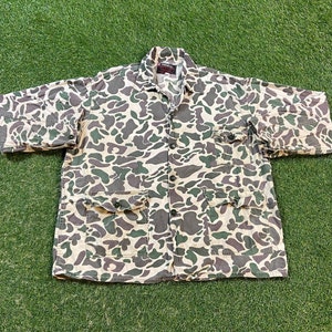 May include: A camouflage print button-up shirt with two large pockets on the front. The shirt is made of a lightweight fabric and has a relaxed fit.