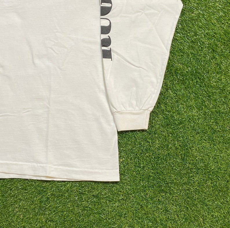 K&ouml;nnte beinhalten: Wei&szlig;es Langarm-T-Shirt mit dem Wort "Donut" vertikal auf dem linken &Auml;rmel gedruckt.