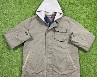 Puede incluir: Una chaqueta verde con capucha, cierre de cremallera y logotipo de Tommy Hilfiger en el pecho. La chaqueta tiene dos bolsillos en la parte delantera y dos bolsillos en el interior.