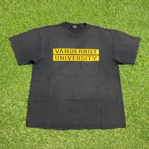 May include: Black t-shirt with the text "VANDERBILT UNIVERSITY" in yellow block letters. The text is centered on the chest. The shirt is short-sleeved and has a crew neck.