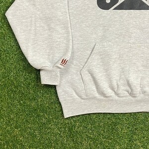 May include: Gray hooded sweatshirt with a black graphic on the front and a brown "WACO" logo on the left sleeve.