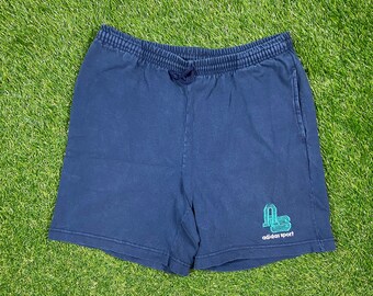 May include: Navy blue athletic shorts with an embroidered green and white Adidas Sport logo.