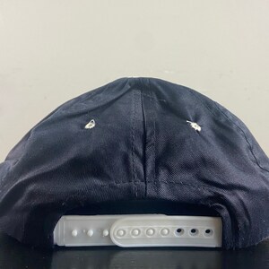 May include: Black baseball cap with a white adjustable strap. The cap is made of a soft, textured fabric.