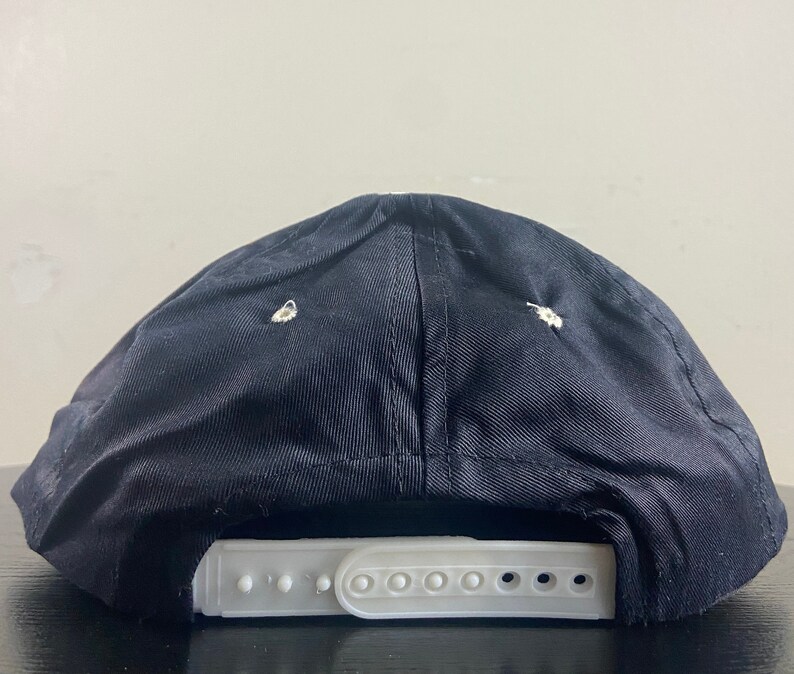 May include: Black baseball cap with a white adjustable strap. The cap is made of a soft, textured fabric.