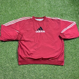 May include: Red Adidas windbreaker with white stripes and a black Adidas logo on the front.
