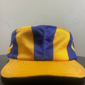 May include: A yellow and blue striped baseball cap with a curved brim.