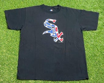 May include: Black t-shirt featuring the Chicago White Sox logo in red, white, and blue. The logo is a stylized "SOX" design with stars and stripes. The shirt is made of a soft material and has a crew neck.