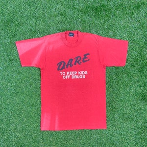 Puede incluir: Camiseta roja de manga corta con texto negro que dice "D.A.R.E. TO KEEP KIDS OFF DRUGS".