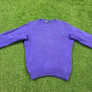 May include: A purple knitted sweater with a small logo on the chest.