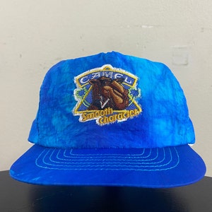 Könnte beinhalten: Eine blaue Batik-Baseballkappe mit einem weißen gestickten Aufnäher, der ein Kamel und den Text "Camel Smooth Character" zeigt.