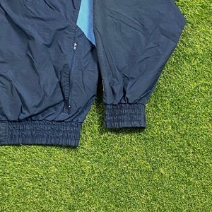 Peut inclure: Une veste coupe-vent bleu marine avec une fermeture &eacute;clair et une doublure &agrave; motifs bleu et blanc. La veste a une taille et des poignets c&ocirc;tel&eacute;s.